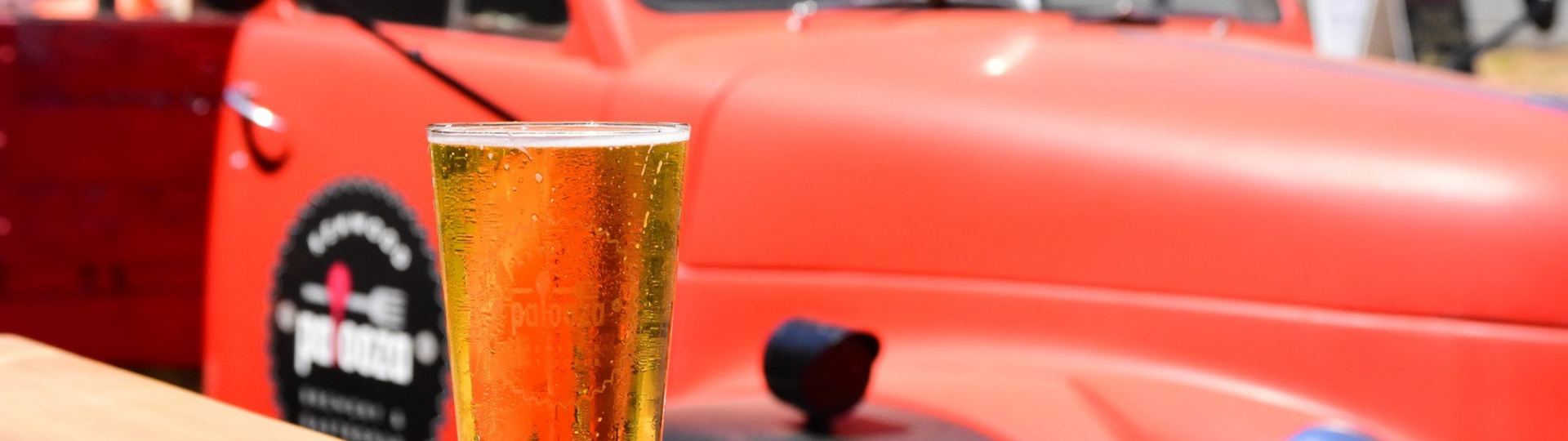 glass of beer on table, red classic pick up truck in background
