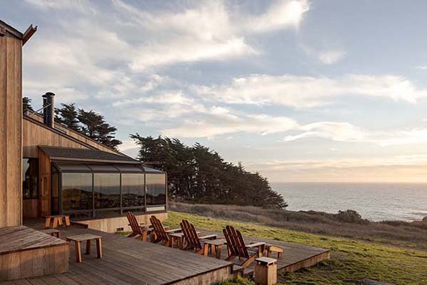 Outdoor chairs looking over coastal bluff outside of lodge.