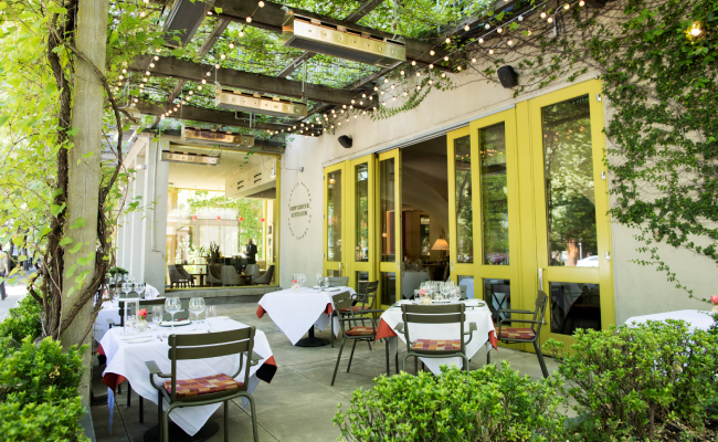 Dry Creek Kitchen seating area with lights, greenery, and open space.